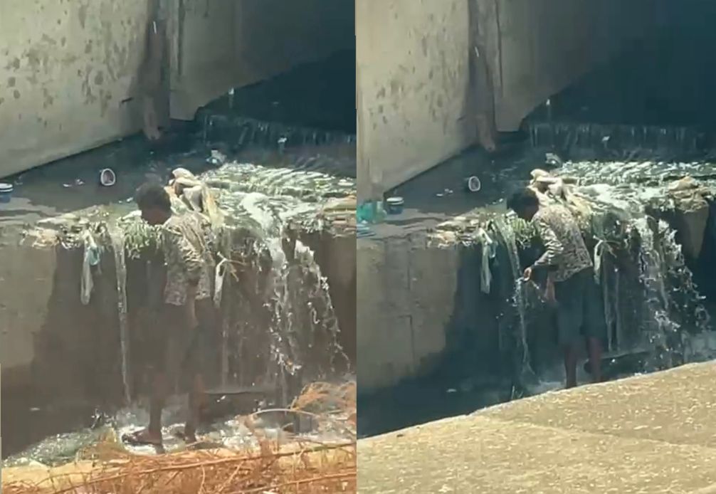 Homem de Rua Se Refresca em Córrego Poluído